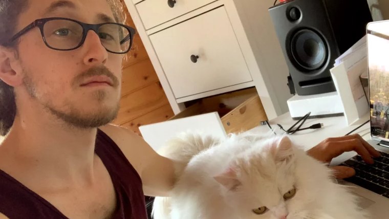 Bastien à son bureau, imperturbable, avec son chat blanc